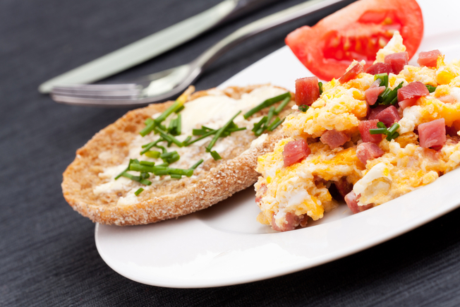Creamy scrambled eggs with ham, tomatoes and roasted peppers 